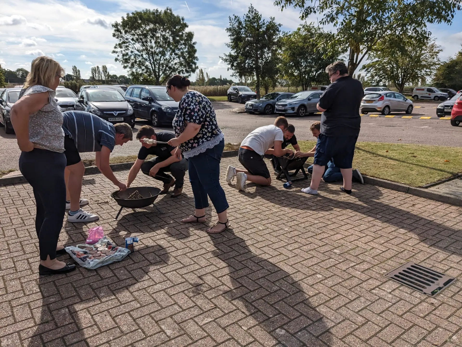 People around firepits in the carpark, team building